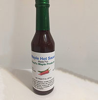 glass container of maple hot sauce